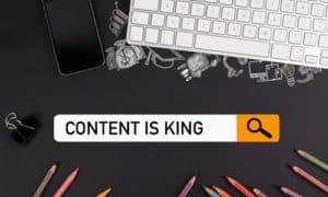 Laptop and smartphone on desk with graphical website search box containing the words content is king