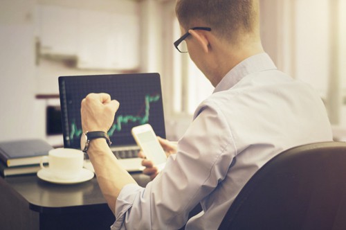 Excited businessman at a desk reviewing the results of his sales after an email marketing campaign