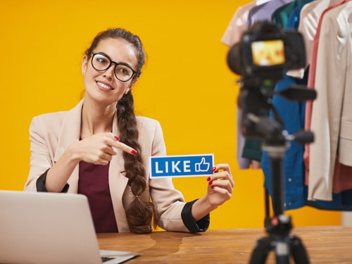 Female business owner holding a Like sign talking about her clothing line on Facebook live stream