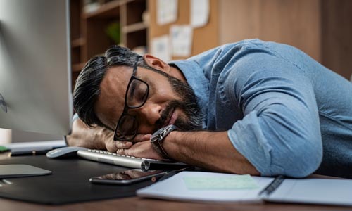 Tired businessman sleeping in office on computer keyboard after working all night on website design