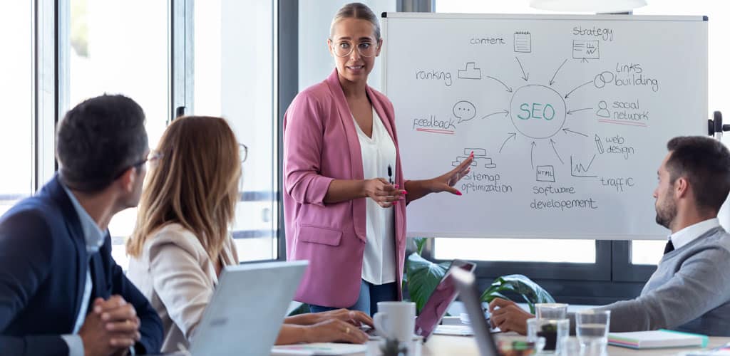 A female digital marketer presents white board to group showing benefits of affordable SEO services