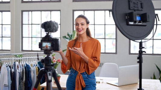 Social influencer standing in front of camera creating online content for her paid media channel