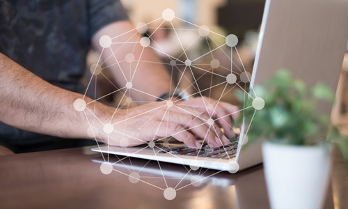 Businessman sitting at desk typing on laptop with graph sphere showing link building in foreground