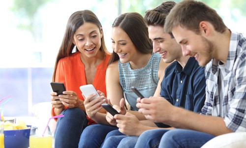 Happy group of friends checking smartphones after seeing a targeted Facebook custom audience ad