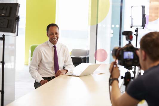 Cameraman recording a businessman in an office setting to create a small business marketing video