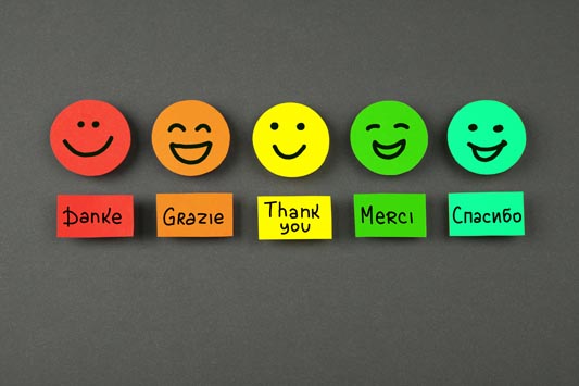 Colorful smiley faces and the word Thank You in several languages on a chalkboard background