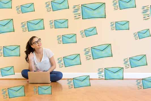 A young female social media influencer sitting on the floor using a laptop to email latest post