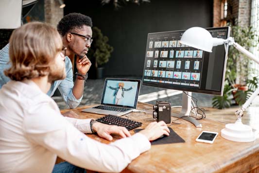 Two local photographers review images at photo studio on computer with vintage camera in foreground