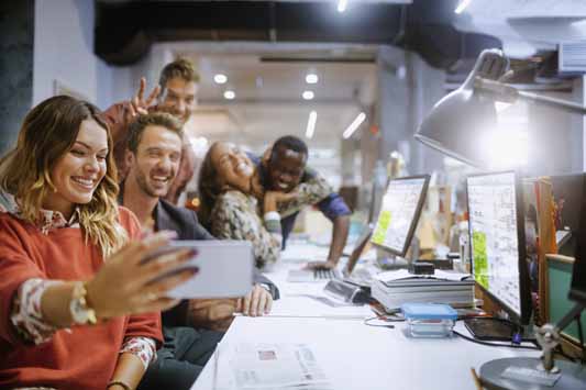 Close up of a group of employees taking a selfie at workstation is good social media management