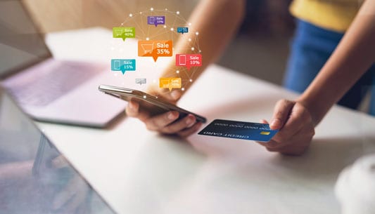 Woman holding credit card and smartphone with flash sale labels jumping off text messaging screen