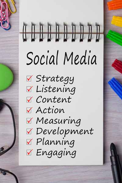 Social Media management checklist with keywords written on notebook and office supplies on a desk