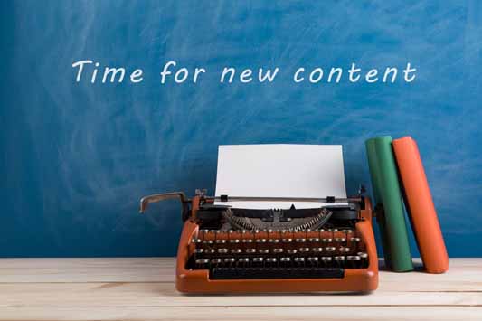 Red typewriter and stationery on blue blackboard background with text "Time for a new content"