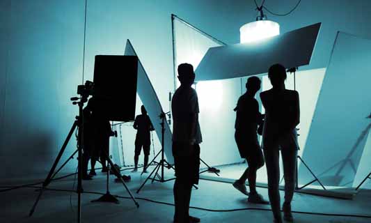 Silhouette of video production crew setting up professional lighting equipment in video studio