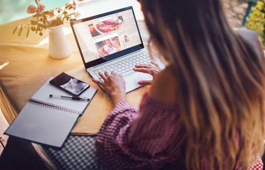 Rear view of young entrepreneur writing copy on laptop from home office for a website landing page