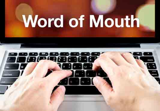 Hands typing on laptop the text Word of Mouth, which you get from customer testimonial videos