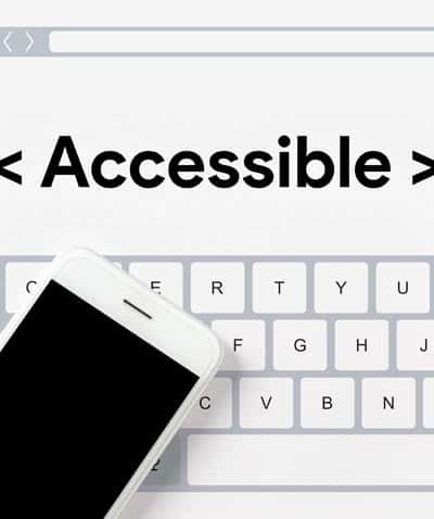 The word accessible between code brackets above keyboard and smart phone for website accessibility