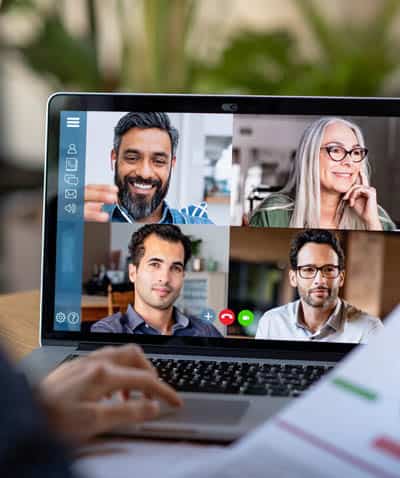 Business owner at desk talking to outsourced marketing team about strategy in remote video session