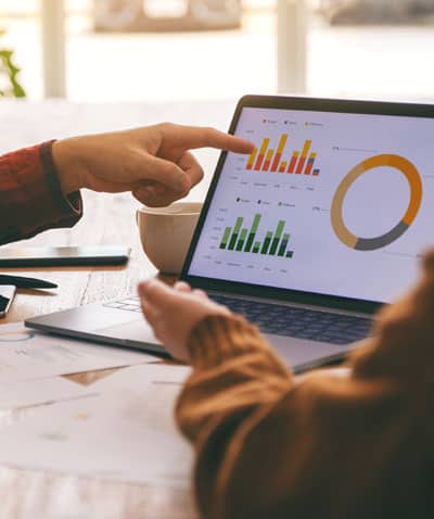 Close up of a hand pointing to a monitor with financial data on it showing improved business growth