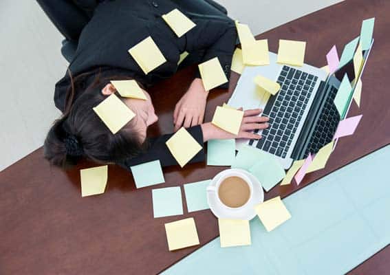 A business owner asleep at desk with post-it notes everywhere after trying do it yourself marketing